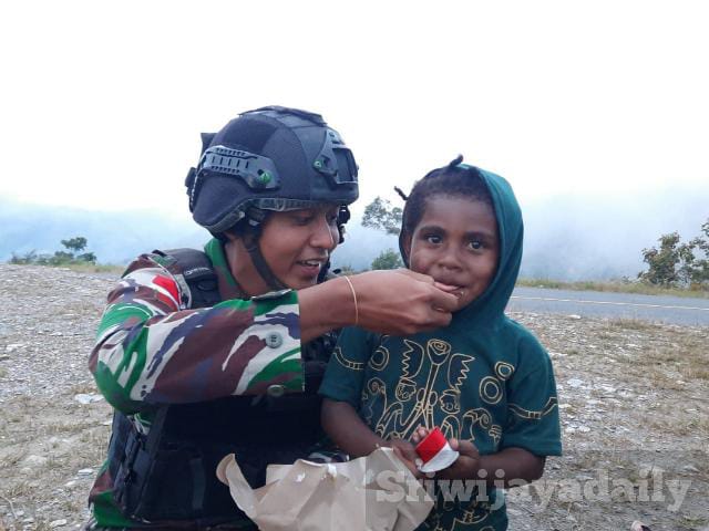 Saat Anggota Posramil Puncak Senyum Satuan Satgas Organik Yonif Rider 301/PKS menyuapi salah satu anak dari warga Distrik Irimuli Kab. Puncak Jaya, Papua. (Pendam Cenderawasih)