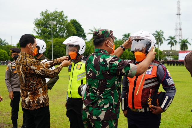 Komandan Korem 042/Gapu Brigjen TNI Supriono, S.IP., M.M secara simbolis memakaikan helm kepada perwakilan peserta Apel Nyata Peningkatan Tertib Berlalu Lintas Provinsi Jambi (Foto. Penrem 042/Gapu) 